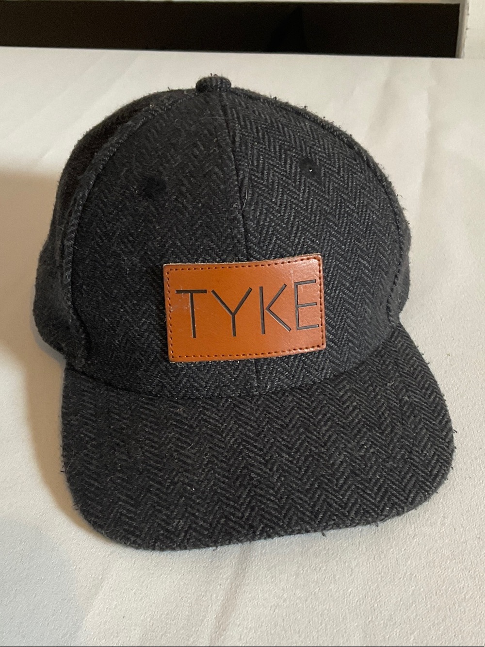 Men’s Black Herringbone Cap with Brown Patch